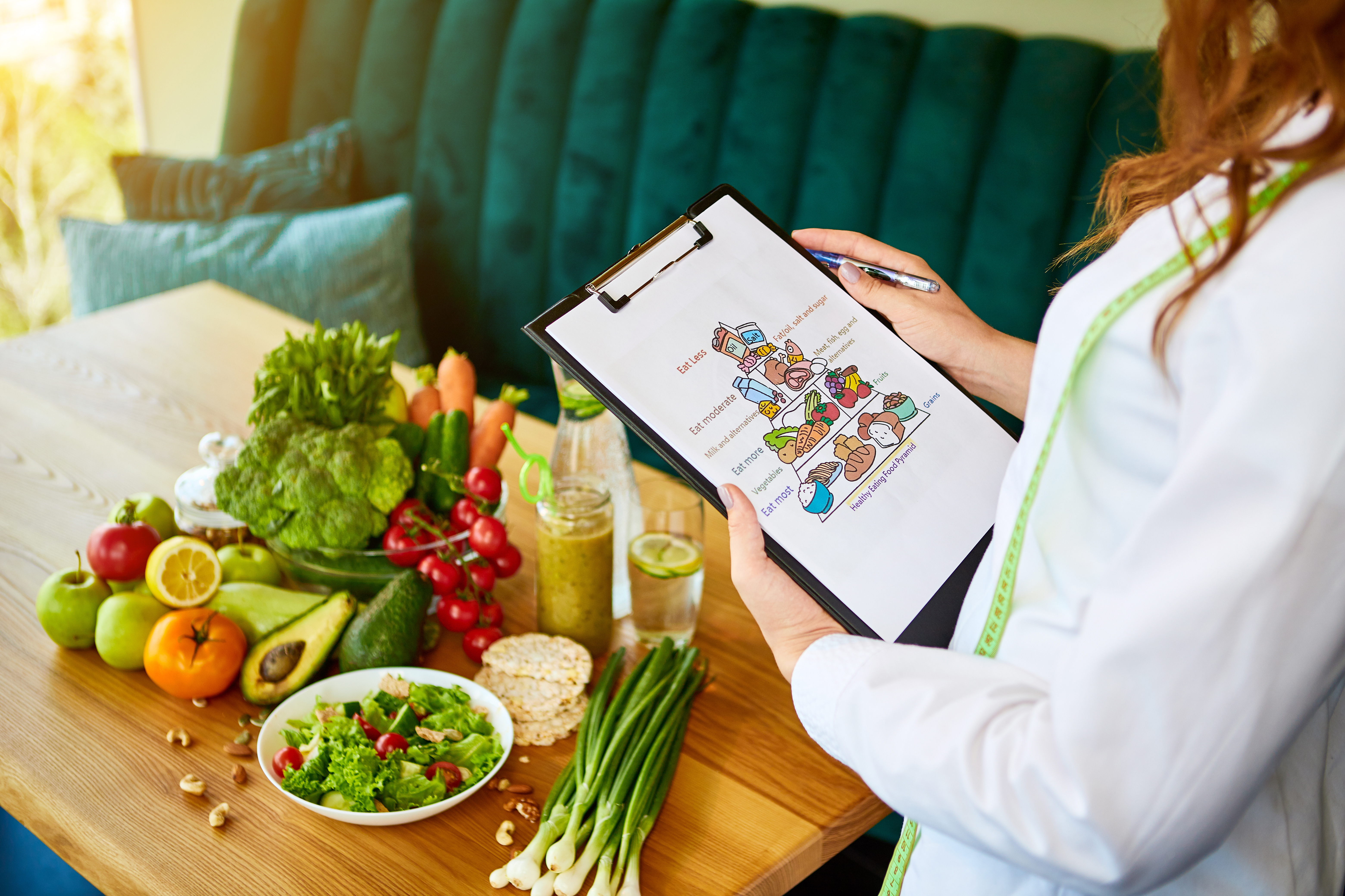 Holding schematic meal plan for diet with various healthy products on the background. Weight loss and right nutrition concept. Eating food pyramid